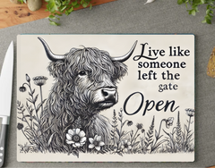 Decorative sign with a highland cow illustration and motivational quote on a wooden surface.