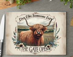 Decorative cutting board with a highland cow illustration and motivational quote on a gray surface.
