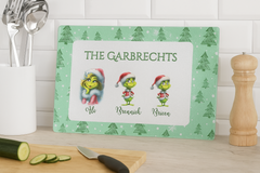 Personalized cutting board with Grinch design and family names on a kitchen counter.
