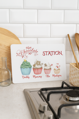 Decorative sign for a hot chocolate station with cartoon cupcakes on a kitchen counter.